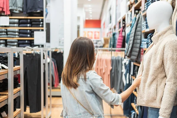 Jonge aziatische vrouw kiezen kleding in kleding winkel in het winkelcentrum — Stockfoto