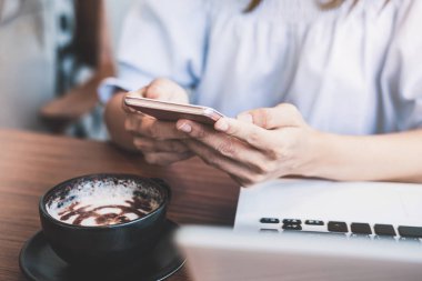 Akıllı telefon ve dizüstü bilgisayar kullanan genç bir kadın.