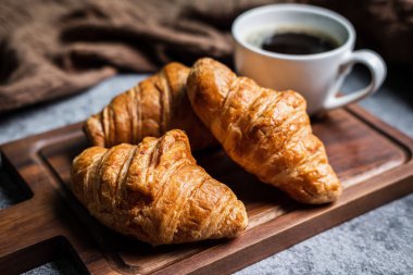 Taze kruvasanlarla kahvaltı ve bir fincan sade kahve.