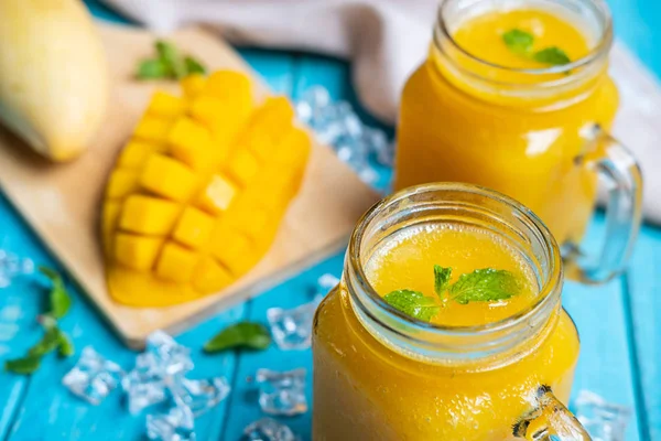 Verfrissende mango smoothies in glas met rijpe mango op houten ta — Stockfoto