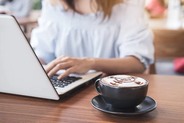 Jovem mulher usando telefone inteligente e laptop com xícara de café em c — Fotografia de Stock
