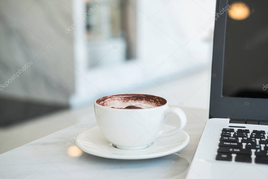 Laptop computer with cup of coffee in cafe