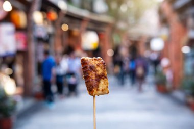 Tayvan sokak yemeklerinde kokuşmuş tofu taşıyan genç bir kadın gezgin, seyahat yaşam tarzı konsepti.