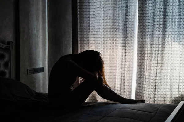 孤独的年轻女子沮丧而紧张地坐在黑暗的卧室里 消极的情感观念 — 图库照片