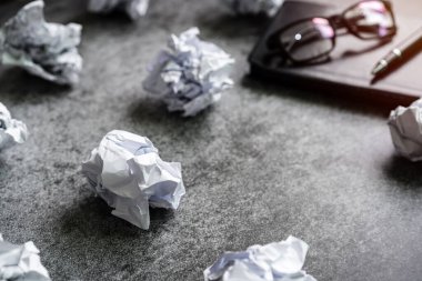 Masasında defter olan buruşuk kağıt toplar, yaratıcılık sorunları kavramı.
