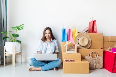 Renkli alışveriş çantası, moda eşyaları ve karton kutuları olan Asyalı genç bir kadın, fotokopi alanı olan internet sitesi alışveriş konsepti