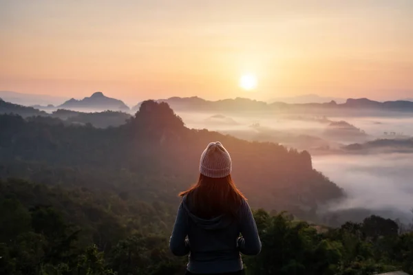 stock image Young woman traveler looking at sea of mist and sunset over the mountain