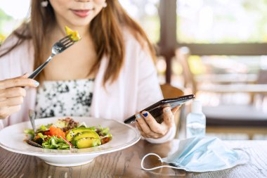 Restoranda yemekten önce Corona virüsü ve bakterisi bulaşmasın diye alkol jeli dezenfektanı kullanan genç bir kadın. Yeni normal yaşam tarzı kavramı.