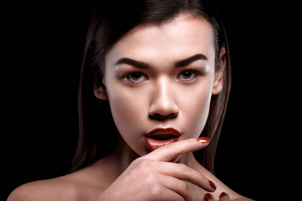 Close up beauty portrait of a girl with bright makeup and manicure on a black background