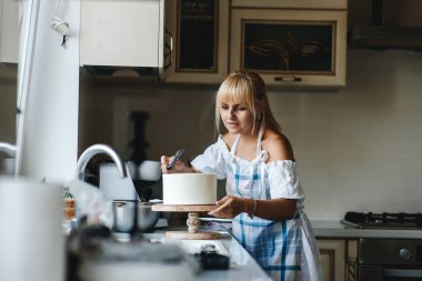 Çekici genç kadın mutfak yemek pişiriyor. Kek ve kurabiye yaparken eğleniyor.