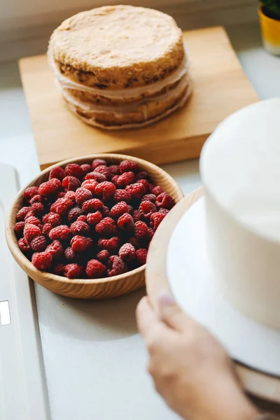 Ragazza panettiere prepara una deliziosa torta di bacche con lamponi freschi e mirtilli Fotografia Stock