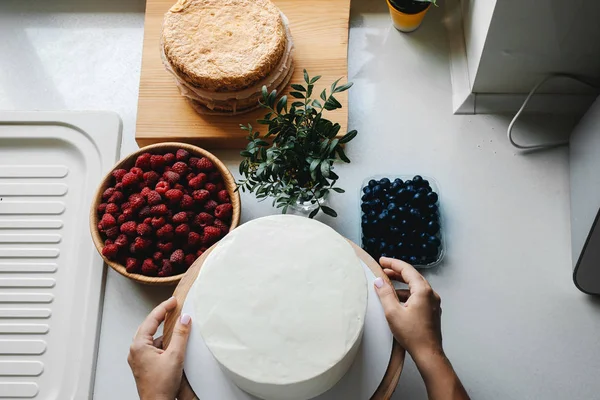 Ragazza panettiere prepara una deliziosa torta di bacche con lamponi freschi e mirtilli Foto Stock