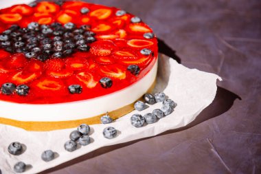 Üstünde çilek, yaban mersini ve çilek reçeli olan soğuk cheesecake..