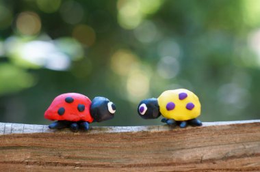 Renkli arka planda plastikten yapılmış iki uğur böceği..