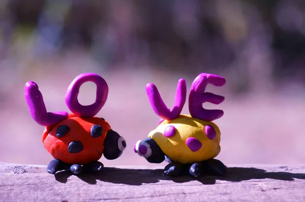 Due Coccinelle Plastilina Sfondo Colorato Accanto Esso Amore Iscrizione — Foto Stock