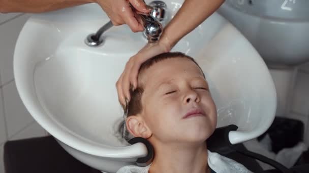 Seorang anak laki-laki yang lucu mengunjungi salon. Shampooing di penata rambut. 4K — Stok Video