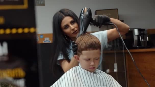 Un chico gracioso visitó la peluquería. Seca el cabello después de cortarlo. 4K — Vídeo de stock
