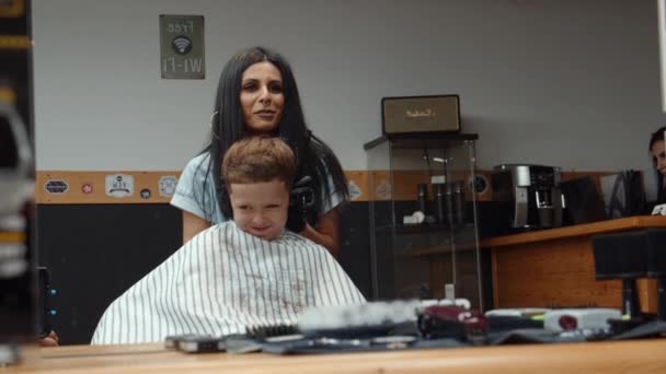 Seorang anak laki-laki yang lucu mengunjungi salon. Rambut kering setelah memotong. 4K — Stok Video