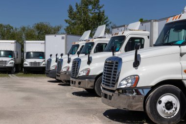 Indianapolis - Circa June 2020: Freightliner Semi Tractor Trailer Trucks Lined up for Sale. Freightliner is owned by Daimler. clipart