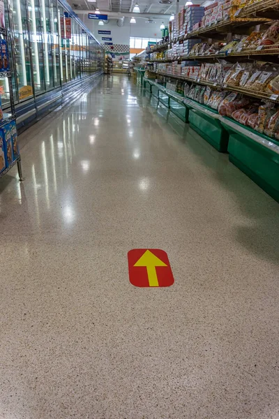 Marca seta amarela no vermelho no chão da mercearia para compras seguras — Fotografia de Stock