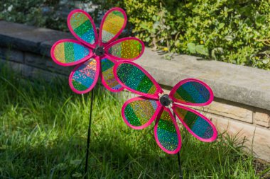 Çok renkli plastik buklelerden yapılmış iki fırıldak akslarına iğnelerle tutturulmuş. Rüzgâr estiğinde dönmek üzere tasarlanmış..
