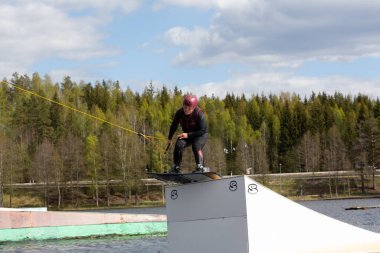 Fagersta, İsveç - Maj 26, 2020: Wakeboardcu wakeboard ile havada uçuyor. Wakeboard ekstrem spordur.