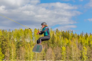 Fagersta, İsveç - 26, 2020 Wakeboard. Genç Wakeboardcu, Wakeboard 'da havada son derece zor bir atlayış yapıyor. Kız gökyüzünde uçuyor