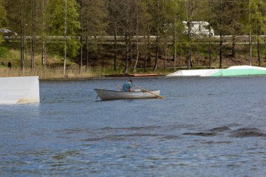 Gölde teknede bir adam telefonuna bakar.