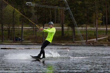 Fagersta, İsveç - Maj 26, 2020: Genç wakeboardcu gölde wakeboard kullanıyor. Wakeboard yapmak çok havalı bir spordur.