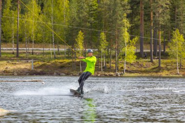 Fagersta, İsveç - Maj 26, 2020: Genç wakeboardcu gölde wakeboard kullanıyor. Wakeboard yapmak çok havalı bir spordur.
