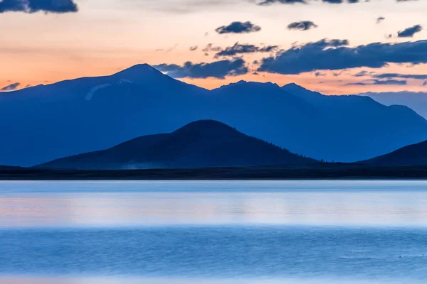 Beautiful blue ridge mountain sunset with orange sky. Mountain Lake in Mongolian Altai.