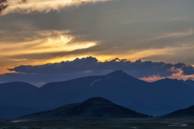 Moğol Altai 'sinde turuncu gökyüzü ile güzel mavi dağ günbatımı.