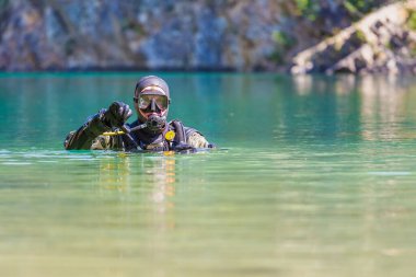 Dalgıç kameraya bakıyor. Baş yüzeyde. Suya girdiğine dair işaretler. başparmaklar aşağı