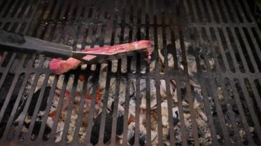 Barbekü ızgarasında biftek pişiriyorum. Çiğ eti tel rafa koy ve diğer tarafa doğru çevir. Zaman aşımı.