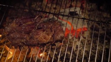 Izgara biftek (orta pişmiş). Zayıf kömürler, kamera hareketleri. 4K, karanlık sahne.