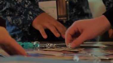 Monopoly oynayan insanların ellerini yakın plan çekeceğiz..