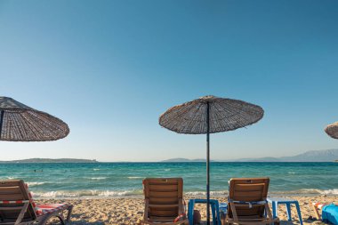 Cesme 'deki kumsal, saman şemsiyeli ve şezlonglu sandalyeli çok güzel bir arka plan..