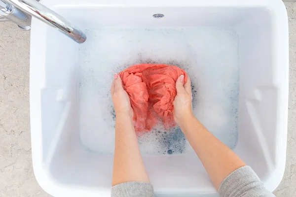 Mãos femininas lavando roupas coloridas no lavatório — Fotografia de Stock