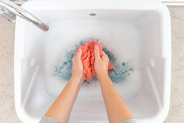 Mãos femininas lavando roupas coloridas no lavatório — Fotografia de Stock