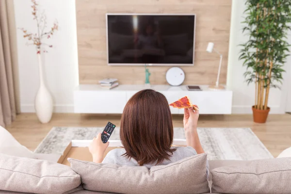 Mujer soltera comiendo pizza y viendo la televisión —  Fotos de Stock