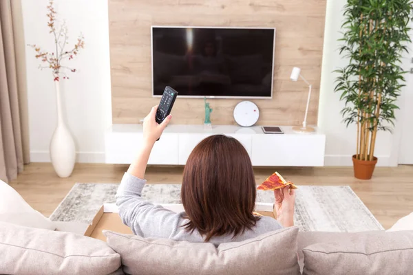 Одна жінка їсть піцу і дивиться телевізор — стокове фото