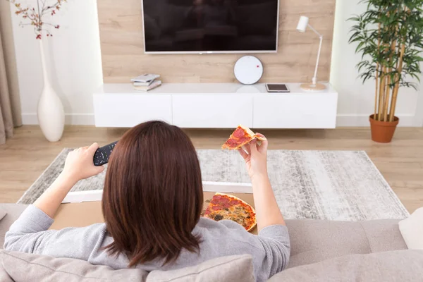 Одинокая женщина ест пиццу и смотрит телевизор — стоковое фото