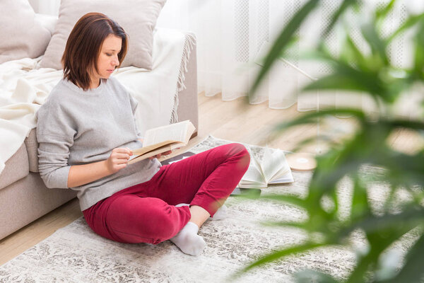 Young woman relaxing on floor at home reading book