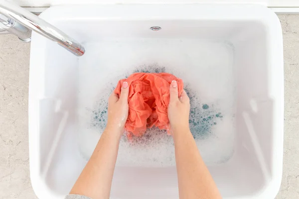 Mãos femininas lavando roupas coloridas no lavatório — Fotografia de Stock