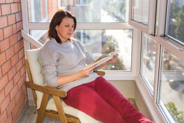 kadın balkonda sıcak güneşli bir günde okuma