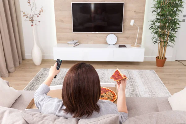 Mujer soltera comiendo pizza y viendo la televisión —  Fotos de Stock