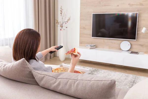 Mujer soltera comiendo pizza y viendo la televisión —  Fotos de Stock