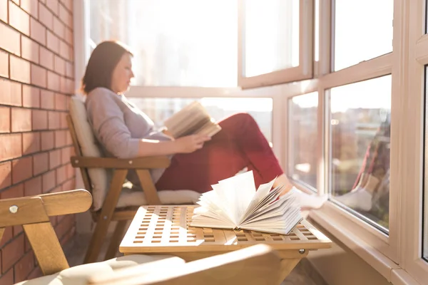 Жінка читає на балконі в теплий сонячний день — стокове фото