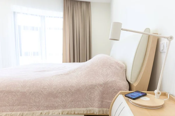 Ricarica smartphone wireless su lampada vicino al letto — Foto Stock