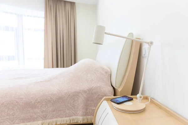 Trådlös smartphone laddning på lampan nära säng — Stockfoto